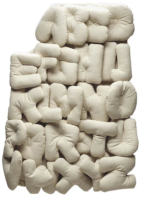 A sculptural artwork or cushion composed of off-white fabric forms shaped into 3D letters spelling 'GET A LOAD OF THIS'.