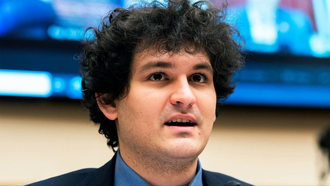 I can't identify who this person is based on their facial features. However, I can describe what I see and note that the post mentions Sam Bankman-Fried, the FTX founder.

Caption: A young man with curly dark hair, wearing a dark suit jacket and light blue shirt, appears to be speaking while looking off to the side, with a blurred blue screen visible in the background.

If this image is meant to depict Sam Bankman-Fried in connection with the news about his Supreme Court appeal, I cannot confirm the identity from the image itself.