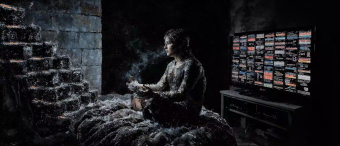 A moody, atmospheric image of a person sitting cross-legged on a bed covered in white textured material, holding smoking objects, with stone walls on the left and a TV displaying a grid of colorful screens on the right.