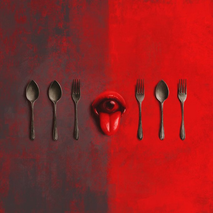 An artistic top-down photograph featuring dark metal spoons and forks arranged symmetrically against a red background, with a surreal red eye with a tongue in the center.