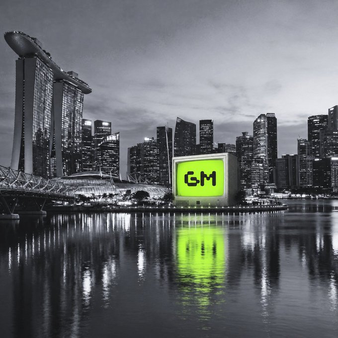 A black and white cityscape of Singapore featuring the Marina Bay Sands hotel, with a bright green screen displaying the "GM" logo in the foreground.