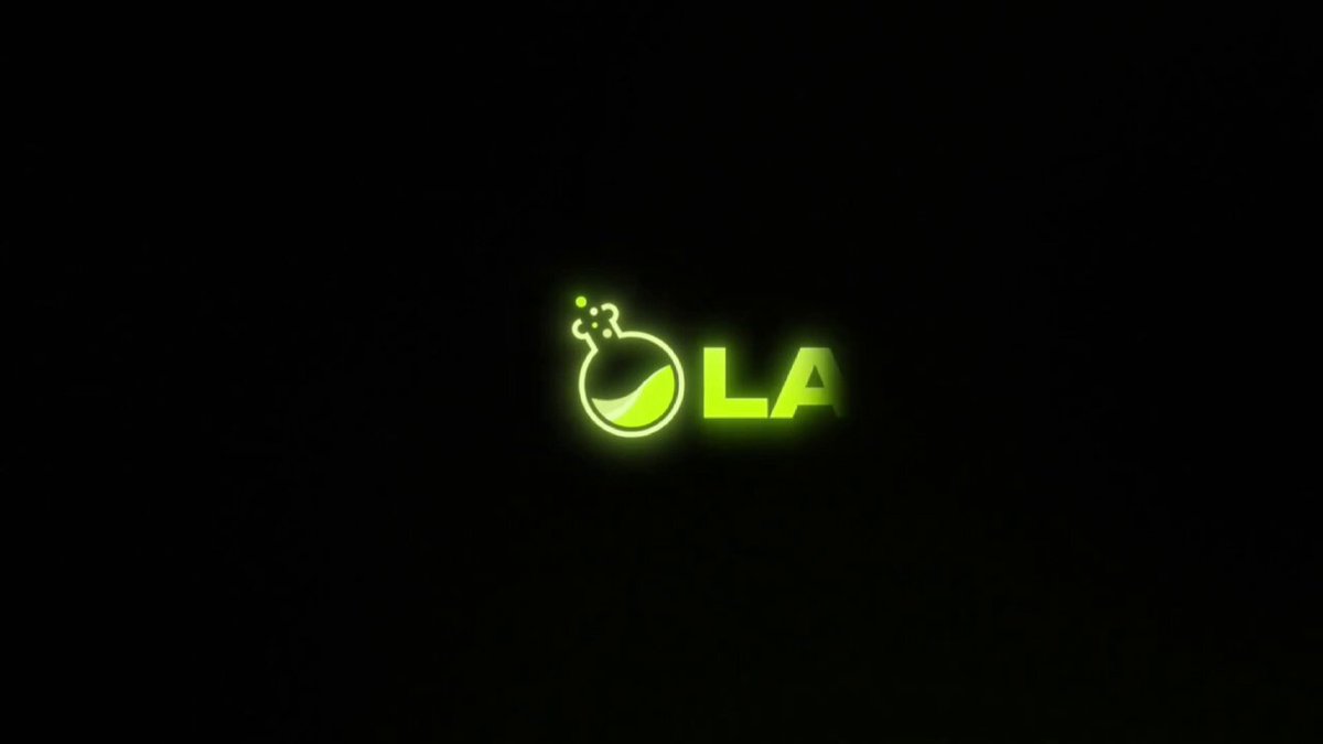 The image is a black and white graphic that features the word "OLA" written in green neon letters above an illustration of a chemical formula, which is a test tube filled with liquid. The text on the graphic is related to laboratory equipment and refers to a mobile app called "@LABtrade_".