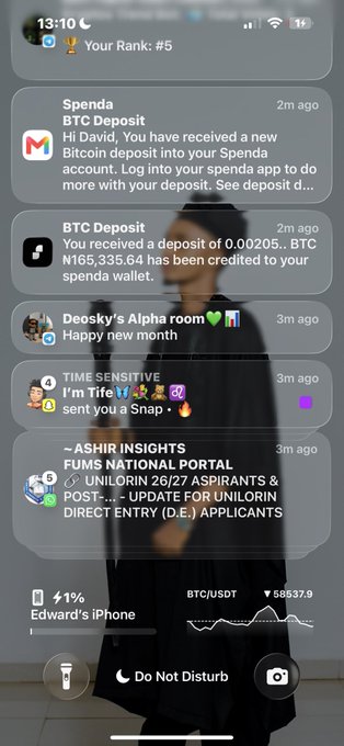 An iPhone lock screen showing notifications from Spenda about BTC deposits, a Snaps message, and F.U.M.S National Portal, with BTC/USDT at $86,637.9, over a blurred background of a person.