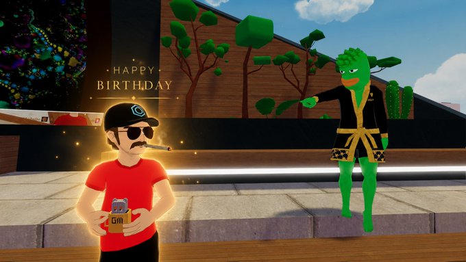 The image features a man wearing sunglasses holding a can of beer while standing next to a woman dressed as a frog with a green outfit. The background includes trees and buildings, suggesting an urban setting. A text overlay reads "Happy Birthday to @decentraland's @alanhowickDCL!!! To another year of conspiracies, coins, zombies, and hosting radio shows".