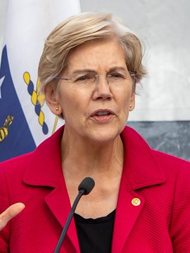 Senator Elizabeth Warren speaks at a podium, likely addressing concerns over the $TRUMP memecoin, with senators urging the SEC to investigate the cryptocurrency as a potential "rug pull."