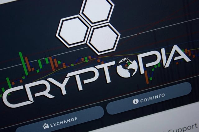 The image shows a close-up of a screen displaying the "CRYPTOPIA" logo and website interface, featuring a honeycomb design, candlestick trading chart, and buttons for "EXCHANGE" and "COININFO." The branding directly relates to the post's question about whether the Cryptopia exchange will distribute ADA, USDT, and Tron (TRX) to its users, as the image represents the platform under discussion.