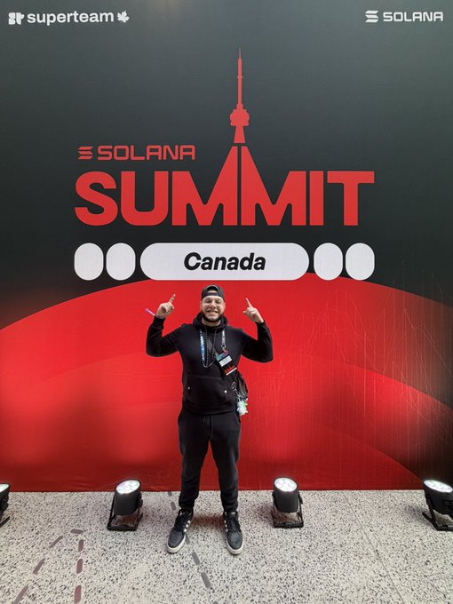 A man poses in front of a 'SOLANA SUMMIT Canada' backdrop with a red CN Tower graphic, featuring logos for Superteam and Solana at the top.