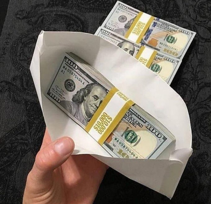 A hand holds open a white envelope revealing multiple banded stacks of $100 bills, each wrapped with yellow straps labeled "$10,000," with additional bundles visible in the background—perfectly capturing the "Get Money" theme of stacking serious cash.