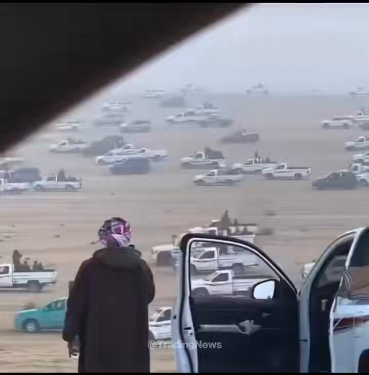 The image shows a man standing next to his car, which has its door open. There are several other cars parked nearby, including some white trucks. The scene appears to be set at an event or gathering where people have gathered around their vehicles. In the background, there is a crowd of people and various vehicles, indicating that it might be a social event or a public gathering. The image also contains text that reads "Liquidity flowing out of Bitcoin for SpaceX IPO". This could possibly be related to the recent news about the IPO of SpaceX, which has been in the headlines recently.