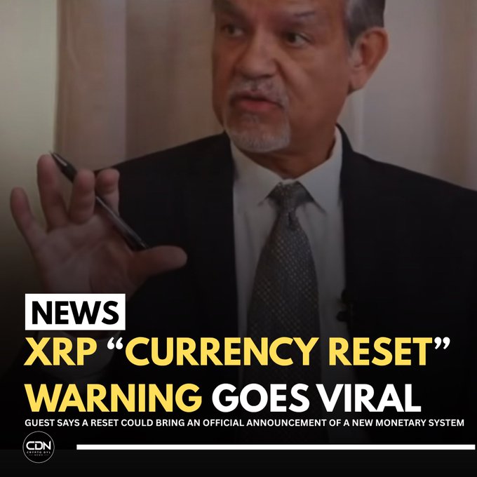 A man in a dark suit gestures while speaking during what appears to be a podcast interview. Overlaid text reads "NEWS: XRP 'CURRENCY RESET' WARNING GOES VIRAL," with a subtitle stating that a guest warns a reset could lead to an official announcement of a new monetary system, aligning with the post's claim about viral XRP reset speculation.