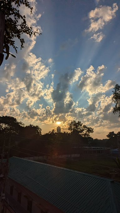 A sunset view over a rooftop with golden sunbeams piercing through scattered clouds, symbolizing fresh optimism and renewed energy to greet the new day.