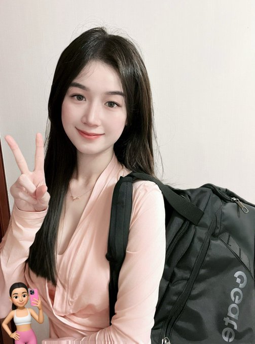 A young woman with long dark hair smiles and flashes a peace sign while wearing a peach-colored hoodie and carrying a black backpack with "a-Gate" branding. The image ties into the post by showcasing Gate's sportswear apparel alongside the fitness and wellness brand mention.