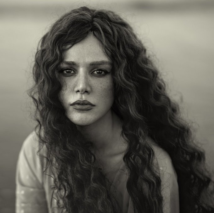 The image features a woman with long, curly hair wearing a white shirt. The photo has been edited to appear black and white, giving it an artistic touch. The caption of the image reads "Good morning Sahar 1/1 edition 180 tezos Link objkt.com/tokens/KT1VRSa". This suggests that the woman's appearance in the photograph is being used as a part of a larger collection or series, possibly for a blog post or social media account.