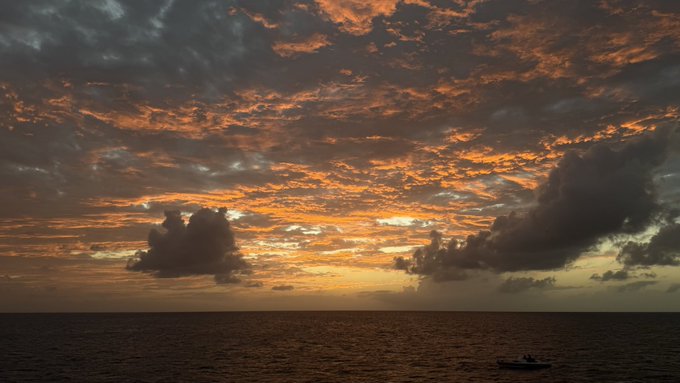A dramatic sunset over the ocean with fiery orange clouds and a small boat on the horizon, symbolically evoking the uncertainty and turbulent transition surrounding Binance's withdrawal of its MiCA application amid Europe's evolving crypto regulations.