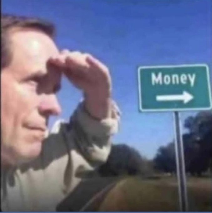 A man shields his eyes with his hand while looking at a green road sign that reads 'Money' with an arrow pointing right.