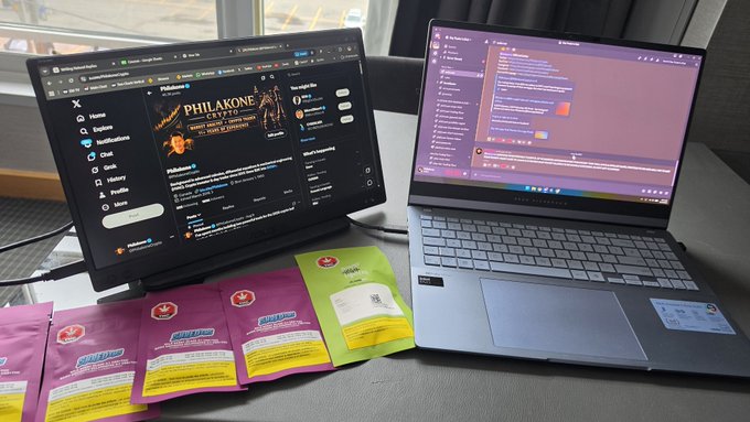 A coding and crypto-themed workspace with two laptops open—one showing the Philakone crypto Twitter page and the other displaying code in an IDE—with several "PinkSale" launchpad cards arranged on the desk, all set up for a productive morning session from Toronto, Canada.
