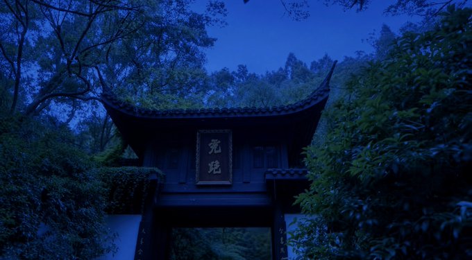 A traditional Chinese gate with a curved roof stands at twilight, featuring a plaque with the characters "宛碧" against a dark blue sky.