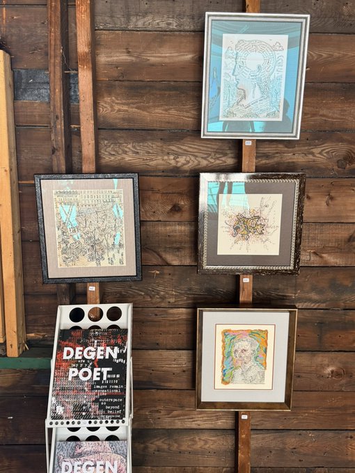 Framed artworks and posters including 'DEGEN POET' displayed on a wooden wall.