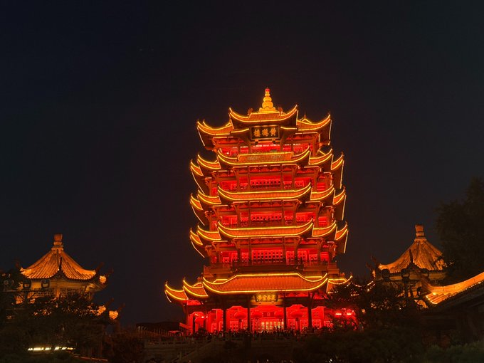 A brightly illuminated traditional Chinese multi-tiered pagoda glowing in red and gold against the night sky.