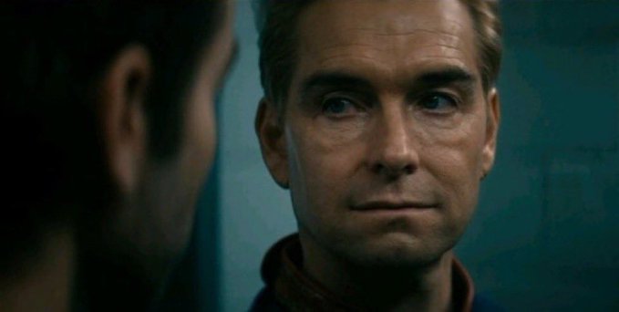 A close-up shot of a man with short hair looking intently at another person whose back is to the camera.
