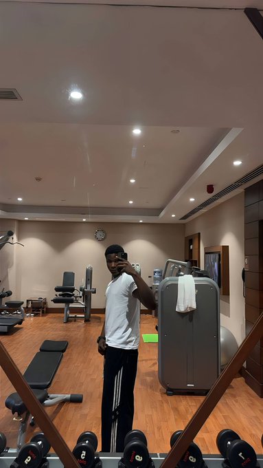 A man films himself in a gym mirror, surrounded by dumbbells and workout equipment. The post contrasts building a Web3-focused “Bull Market 2.0” through his passions, citing gains over $80K in the last bull market and a roughly 70% portfolio loss, with continuing to work rather than waiting for crypto to recover.