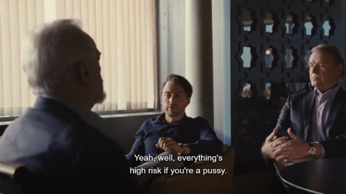 Three men sit in an office discussing risk; the central figure says, 'Yeah, well, everything's high risk if you're a pussy.'