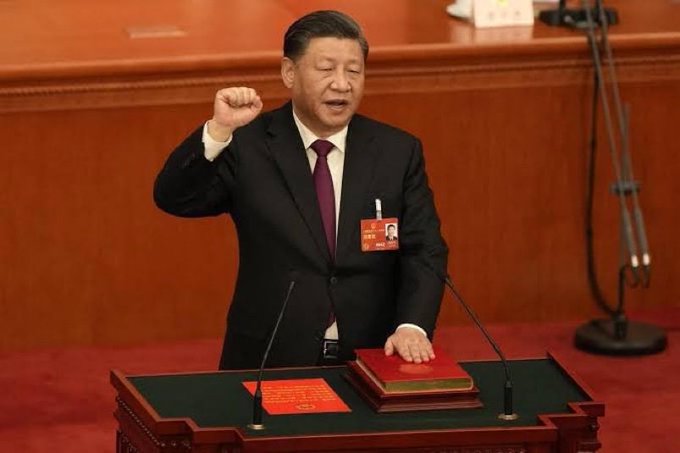 Xi Jinping, with his fist raised and hand on a book, appears onstage while Hong Kong offers 0% capital gains tax on BTC and crypto.
