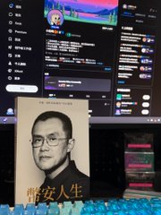 A computer monitor shows streaming software with multiple panels, while in the foreground sits a book with a portrait of a man wearing glasses and Chinese text reading "華安人生".