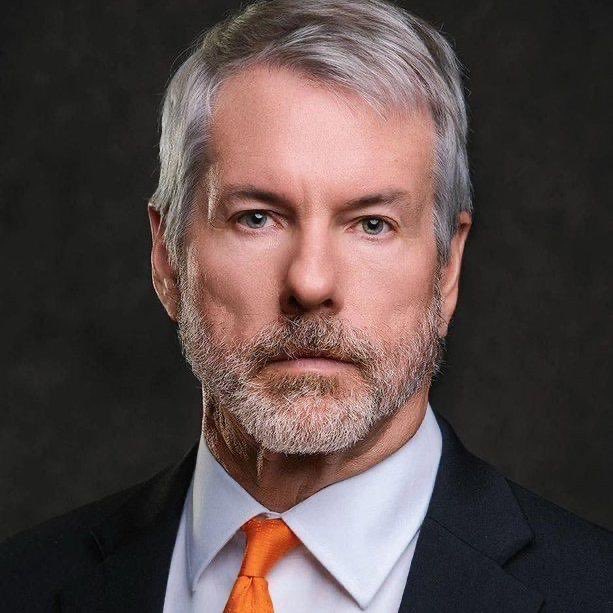 A man with silver hair, a salt-and-pepper beard, and an orange tie looks seriously into the camera against a dark background, his stern expression reflecting the somber news that Strategy (formerly MicroStrategy) raised $333.7M through stock sales last week but did not purchase any Bitcoin.