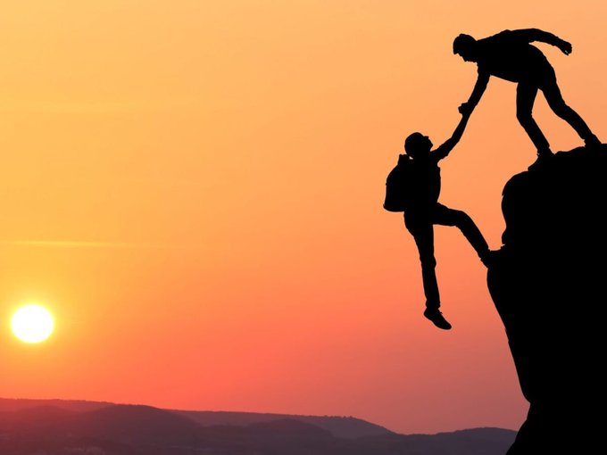 A silhouette captures one climber reaching down from a cliff to pull another up toward safety during a vibrant orange sunset, symbolizing teamwork and mutual support in overcoming challenges. The image mirrors the post's message about the Quasar team rallying together to raise $280k and pursue breakthroughs despite setbacks.