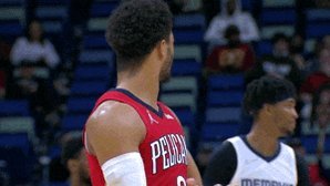 A close-up photo of basketball player Pedulla wearing a red jersey during a game, with other players in white jerseys visible in the background.