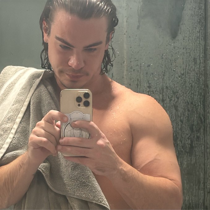 A man with wet hair and a towel draped over his shoulder takes a mirror selfie with an iPhone, showing off his muscular, toned physique. The post's caption "tfw the 230 isn't fat" humorously relates to the image, suggesting he's flexing his lean, fit body to joke that being 230 pounds doesn't mean being overweight—implying instead that it looks like solid muscle.