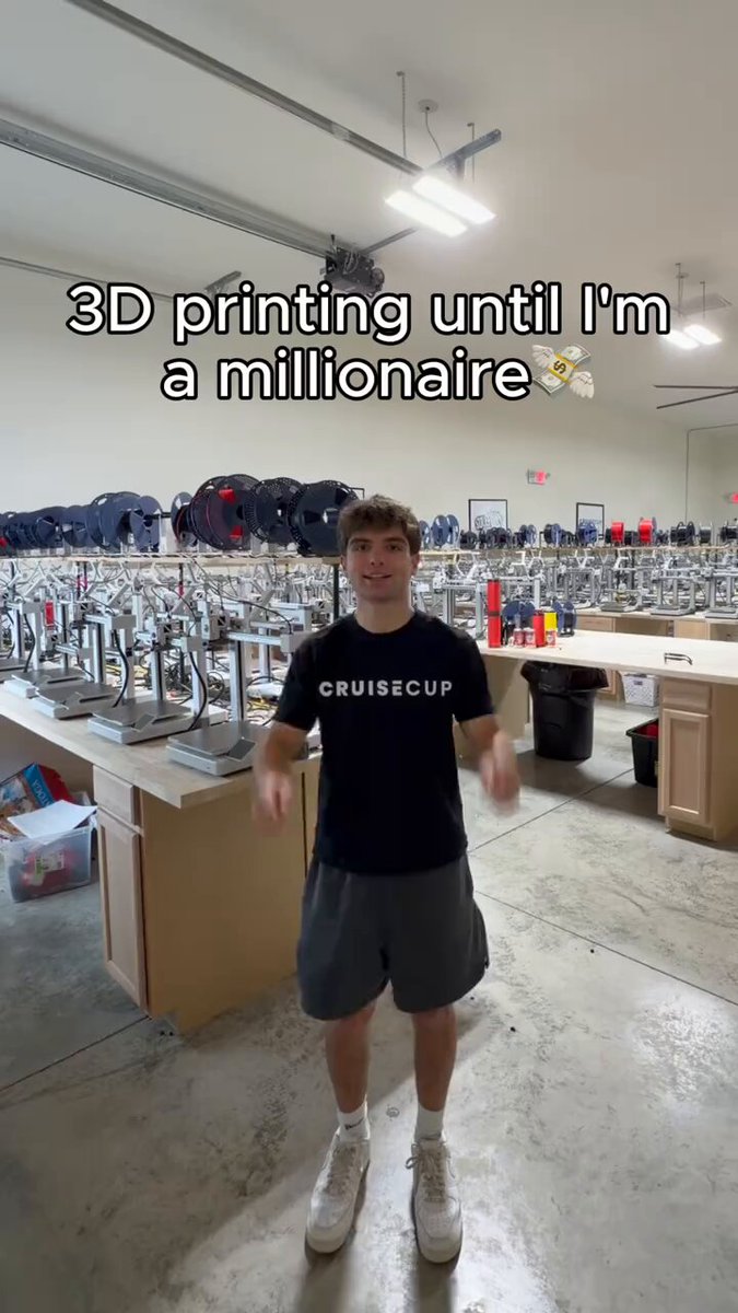 The image features a man standing in front of a desk within a warehouse-like setting. He is wearing a black t-shirt and gray shorts while holding a cup, possibly filled with coffee or another beverage. The text in the image refers to this person as "the 19-year-old guy" who has created one cup for $50 instead of spending money on buying spares at a store. It is suggested that he has made this unconventional cup using his 3D printer and has started producing items with it, likely focusing on creating affordable products such as cups or other everyday objects. The image seems to be an advertisement promoting the idea of making things at home for lower costs compared to traditional methods.