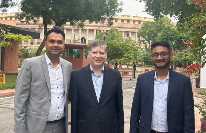 Three professionally dressed men stand together outside the Indian Parliament building, likely representing crypto industry leaders engaging with India's Parliamentary Committee on digital asset policy discussions.