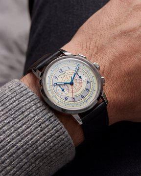 A close-up of a Timex wristwatch with a cream-colored dial, blue hands, and a red seconds hand worn on a wrist with a gray ribbed sweater. The "Timex" branding is visible on the watch face, aligning with the post's enthusiastic reaction that "Timex cooked" — highlighting the watch's stylish, premium-looking design.
