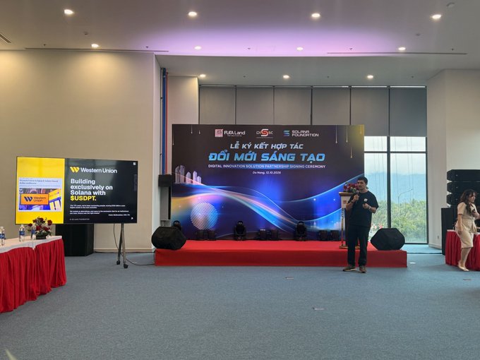 The image captures a man presenting on stage at the "ĐỔI MỚI SÁNG TẠO" (Digital Innovation and Creative Partnership Signing Ceremony) in Vietnam, with a Western Union slide discussing USDPT and Solana visible on a screen—tying into the post's mention of meeting Solana teams in the country. Logos for FUELHOME, Solana, and Solidus Labs Foundation are displayed on the main banner behind the speaker.