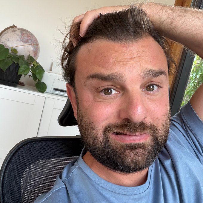 A man with a beard sits in an office chair, running his hand through his hair with a concerned expression, against a backdrop of a globe and a houseplant. The image likely reflects the tension and anticipation surrounding the "BIG FED DAY" mentioned in the post, where his worried look could symbolize market anxiety as Ethereum ($ETH) tests the crucial $2,000 support level amid Federal Reserve decisions.