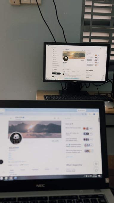 A desk setup with a Dell monitor displaying what appears to be a YouTube channel page, with an NEC laptop in the foreground also showing a similar webpage.