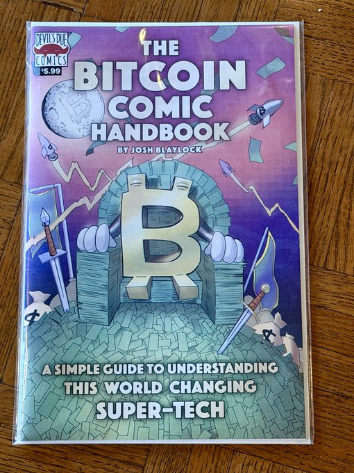 The cover of 'THE BITCOIN COMIC HANDBOOK' by Josh Blaylock, priced at $5.99, subtitled 'A simple guide to understanding this world changing super-tech,' showing a stylized 'B' emblem on a castle backdrop.