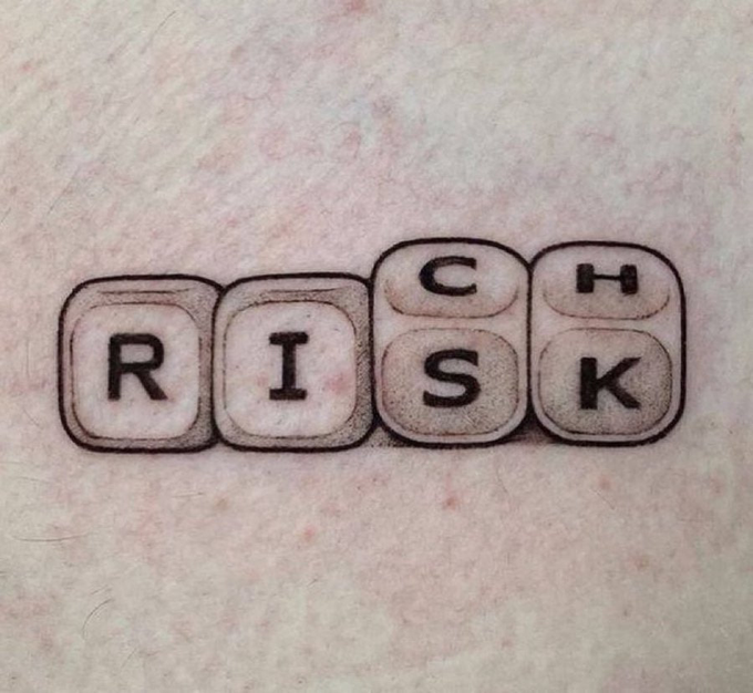 A tattoo on skin depicts four keyboard keys spelling "RISK," with the "C" and "H" keys positioned above the "S" and "K" to form "RISCH," a clever visual play on the phrase "No risk, no rich" by incorporating the extra letters through key placement.