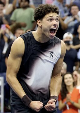 A young tennis player with curly hair, wearing an "On" branded sleeveless athletic shirt, is shown screaming passionately with clenched fists, visibly celebrating a victory—fittingly illustrating the post about the massive $189k Polymarket bet on Ben Shelton to win against Frances Tiafoe.