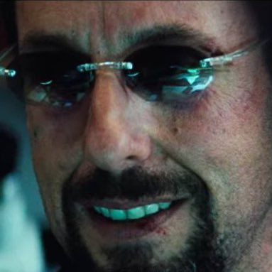 A close-up of Tony Stark (Robert Downey Jr.) wearing rimless sunglasses with a subtle smirk.