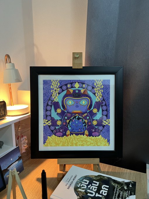 A framed colorful illustration of a mystical character (labeled 'STEP') with a blue face and ornate headdress sits on a wooden easel on a desk, with a book titled 'BROKEN KING' visible below.