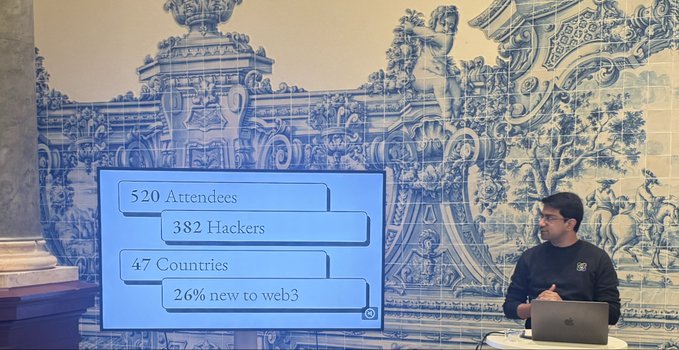 A presenter stands at a laptop in front of a screen showing conference statistics: '520 Attendees, 382 Hackers, 47 Countries, 26% new to web3' against an ornate blue and white tile background.