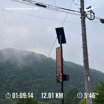 A Garmin Forerunner 265 activity overlay on a photo of a misty mountain road and utility pole, showing a Japanese temperature sign, 12.01 km distance, 1:09:14 time, and 5'46" pace.