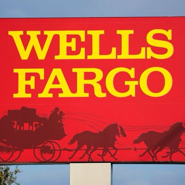 A bright red Wells Fargo bank sign featuring yellow text and a silhouette of a stagecoach pulled by two horses.