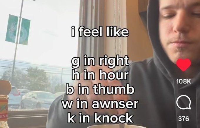 A man in a hoodie sits in a cafe with text overlay reading 'i feel like g in right, h in hour, b in thumb, w in awnser, k in knock' showing 108K likes and 376 comments on what appears to be a TikTok video.