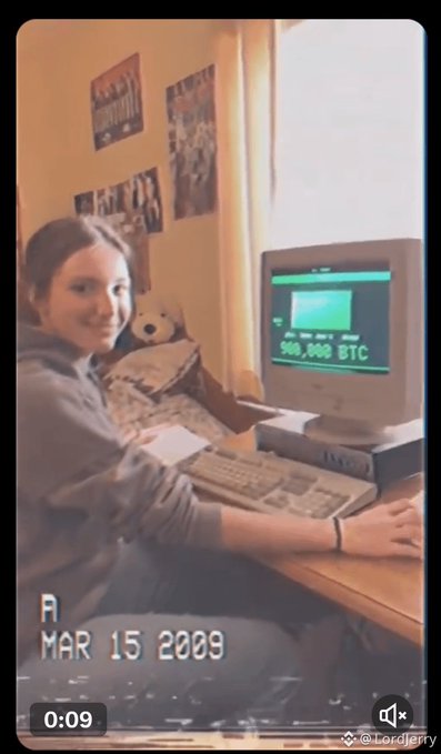 A vintage-style photo dated "MAR 15 2009" showing a young woman smiling at a CRT computer displaying "500,000 BTC" on screen, with the image framed like a dated photograph and watermarked "@LordJerry" with a 0:09 video indicator.