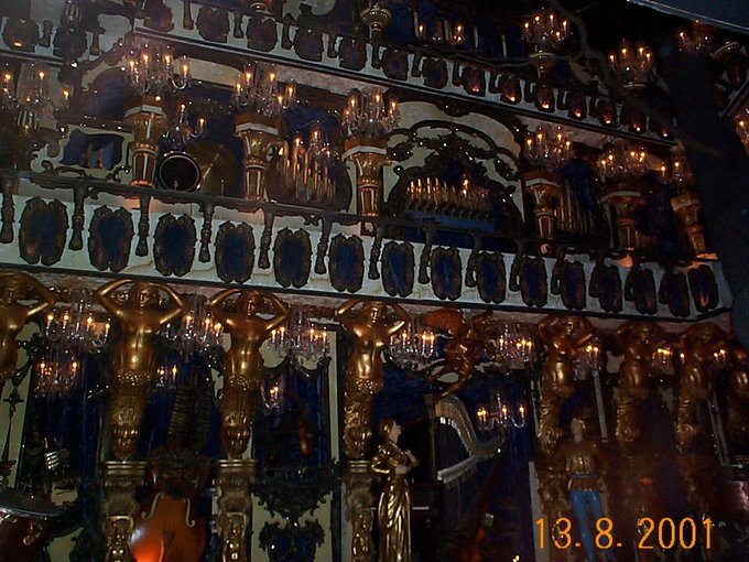 An ornate, gold-decorated interior, possibly a chandelier display in a palace or cathedral, features rows of candle-lit fixtures and intricate metalwork, with a date stamp reading '13.8.2001'.