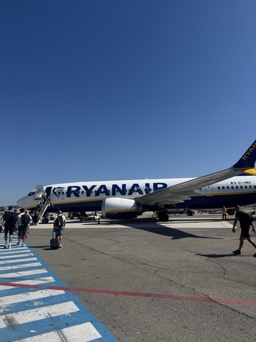 Passengers are walking on the tarmac toward a blue and white Ryanair jet (registration EI-IMN) under a clear blue sky. The image likely captures the poster's evening travel journey, with the plane ride setting the stage for a relaxing arrival and upcoming unwind.